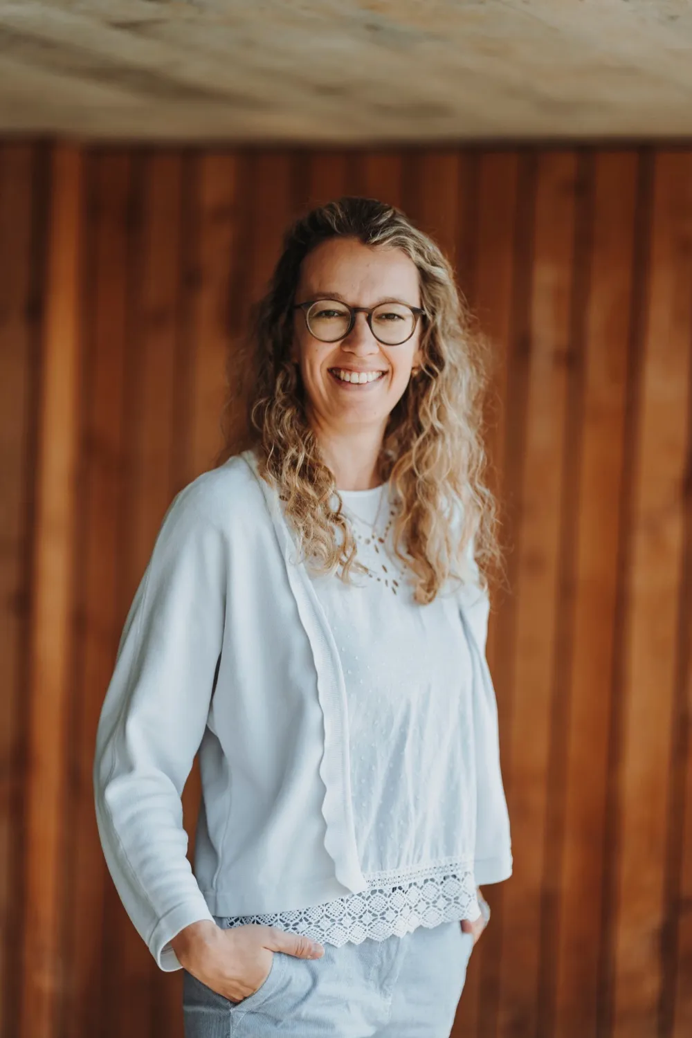 Patricia Furrer, lächelnd vor einer Holzwand